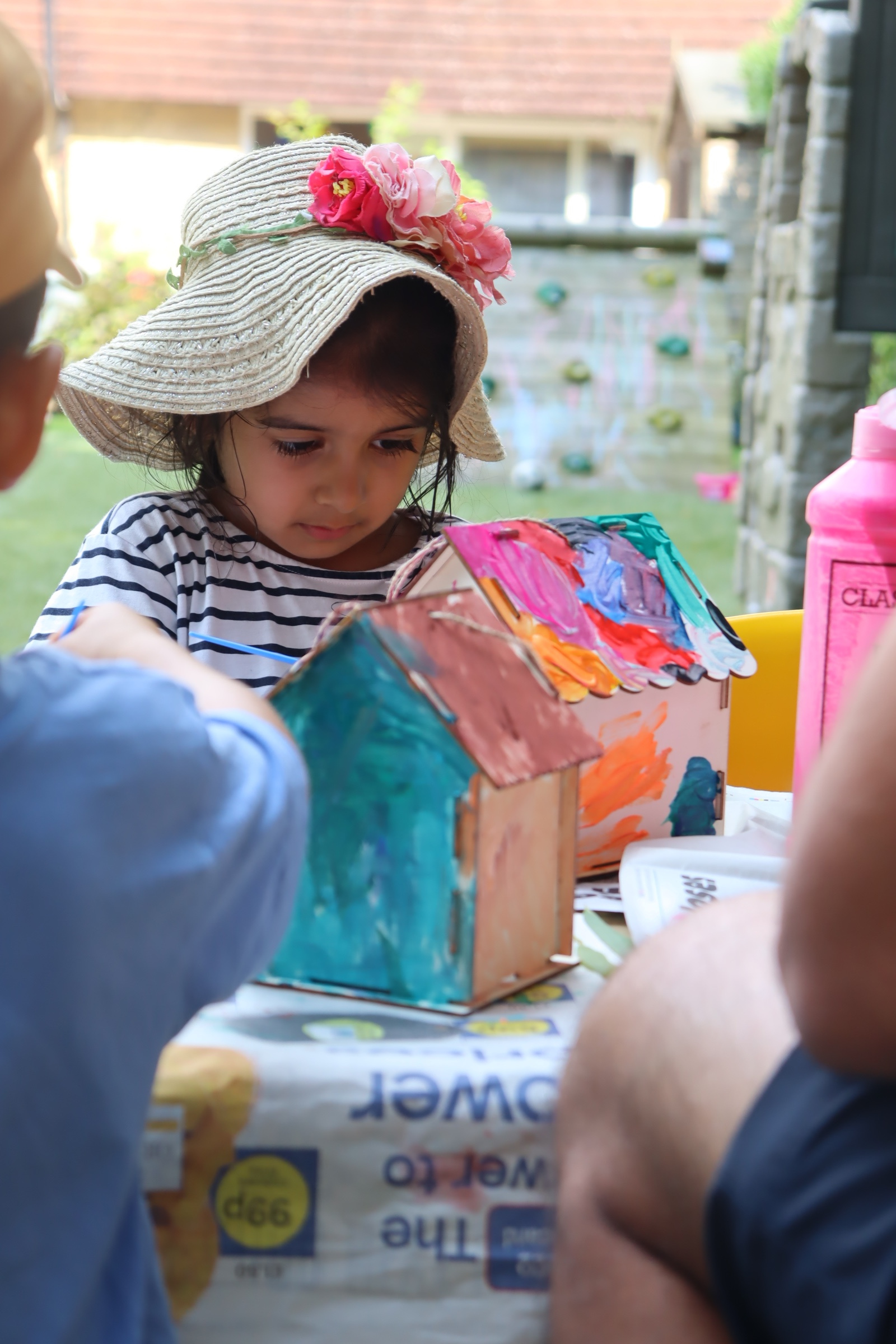 a little learner painting a birdhouse